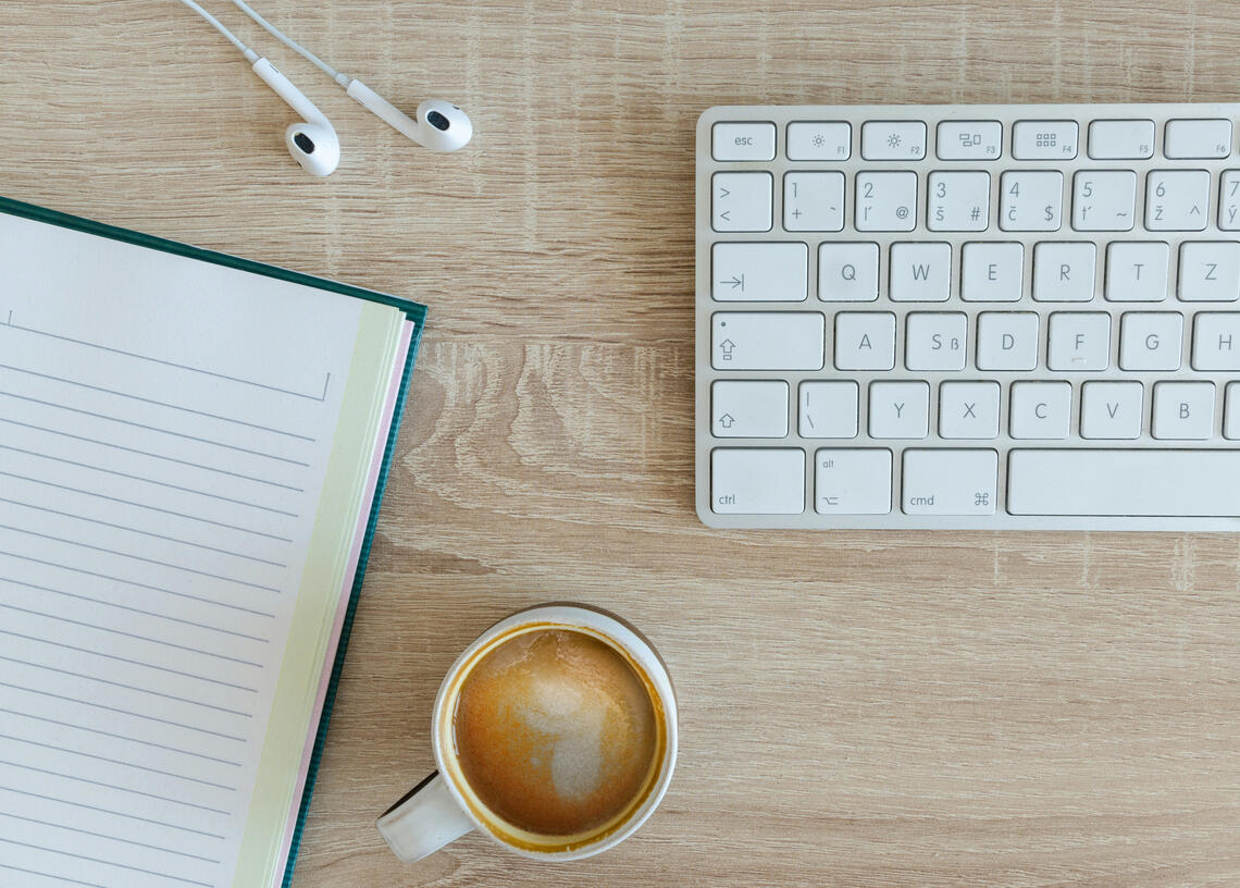 Notebook, keyboard, and coffee on a desk set up for online Spanish lessons