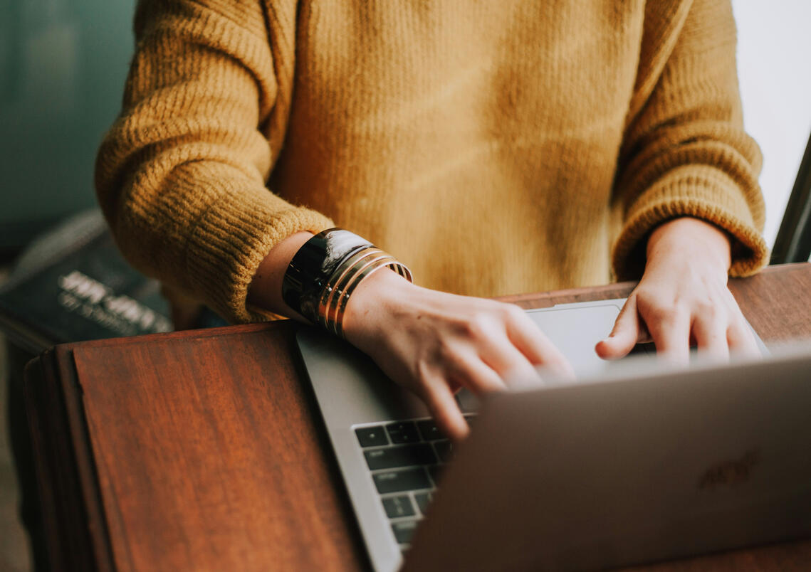 Person typing on a laptop while taking an online Spanish lesson